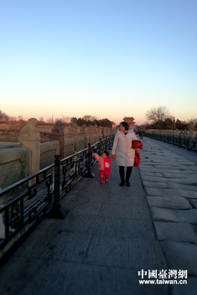 落日余晖倾洒卢沟桥，一位年轻妈妈带着2岁的女儿参观卢沟桥