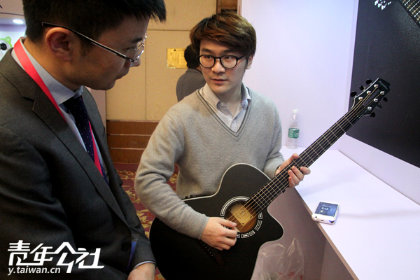 青年创业展览区内，工作人员向嘉宾演示创业产品“智能吉他”